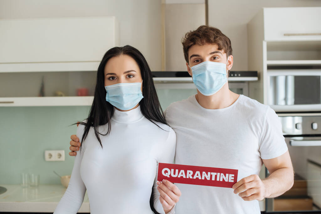 pareja enferma con máscaras médicas sosteniendo el signo de cuarentena en casa durante el autoaislamiento
 - Foto, Imagen