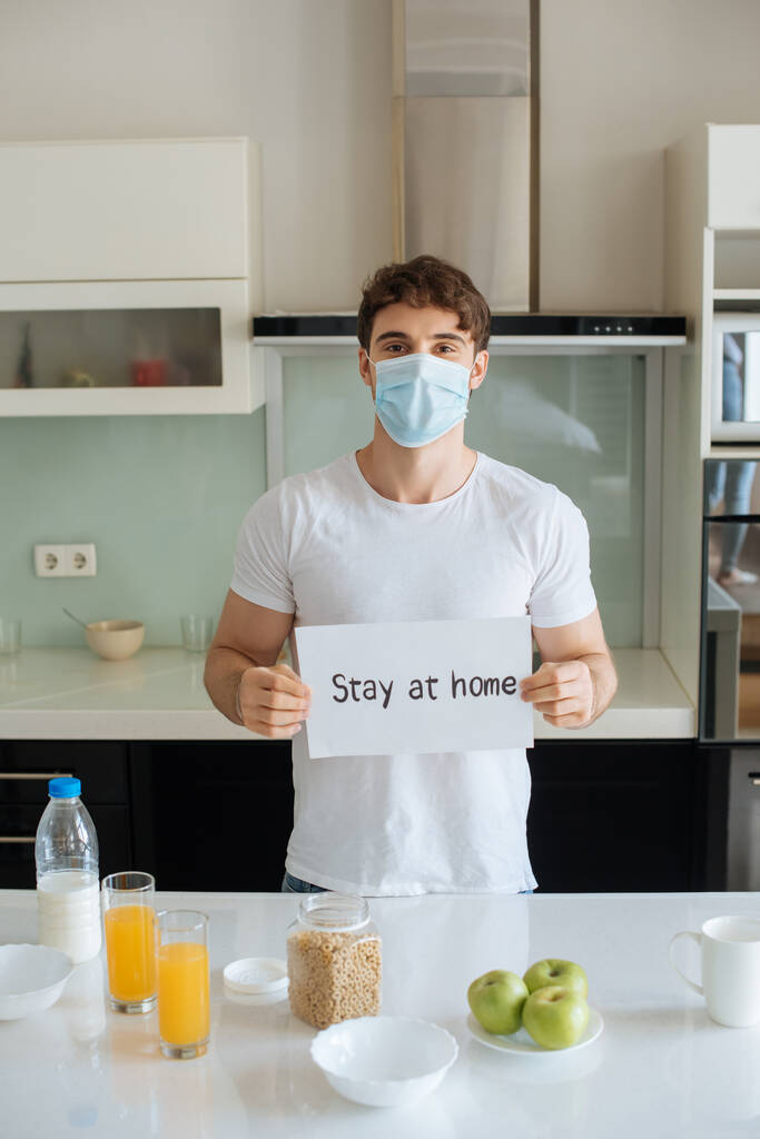 malade en masque médical tenant séjour à la maison carte sur la cuisine pendant le petit déjeuner sur l'isolement personnel
  - Photo, image