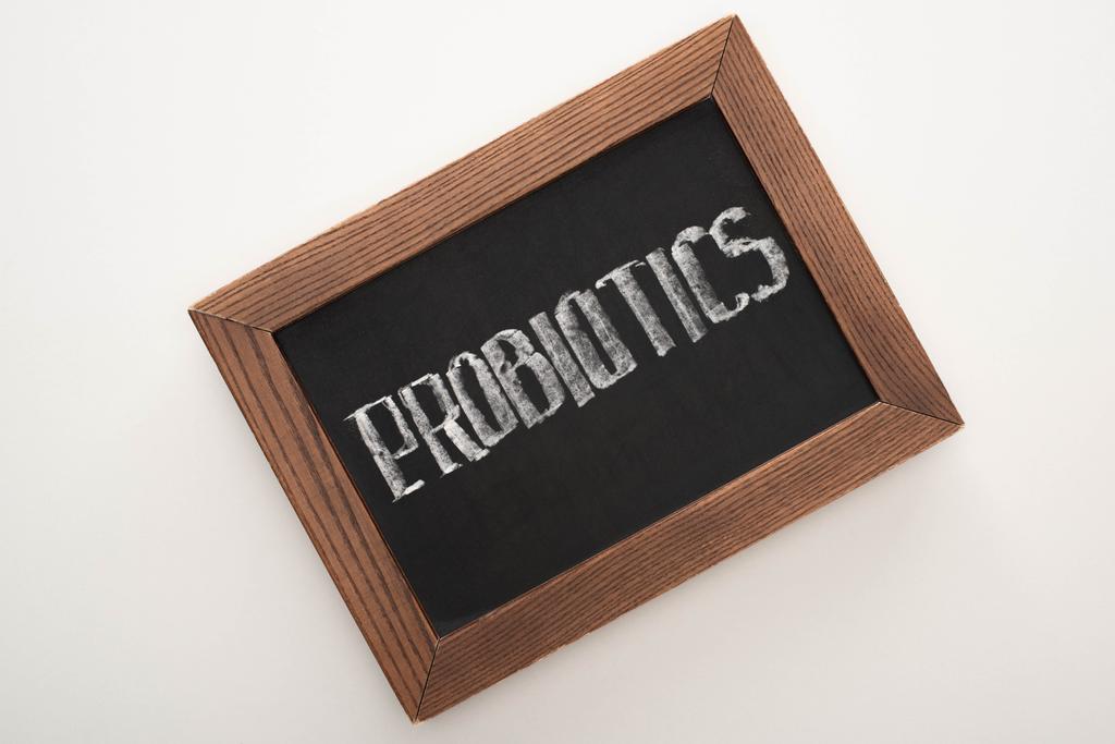 bovenaanzicht van krijtbord met probiotica letters op witte achtergrond - Foto, afbeelding