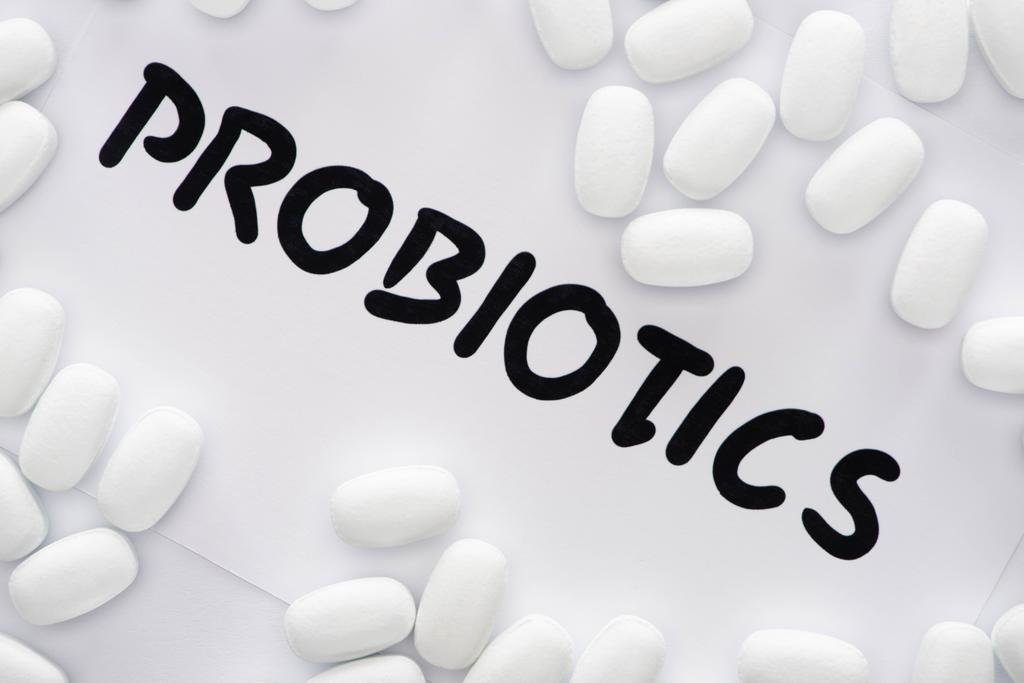 vista dall'alto di carta con probiotici lettering e pillole su sfondo bianco
 - Foto, immagini