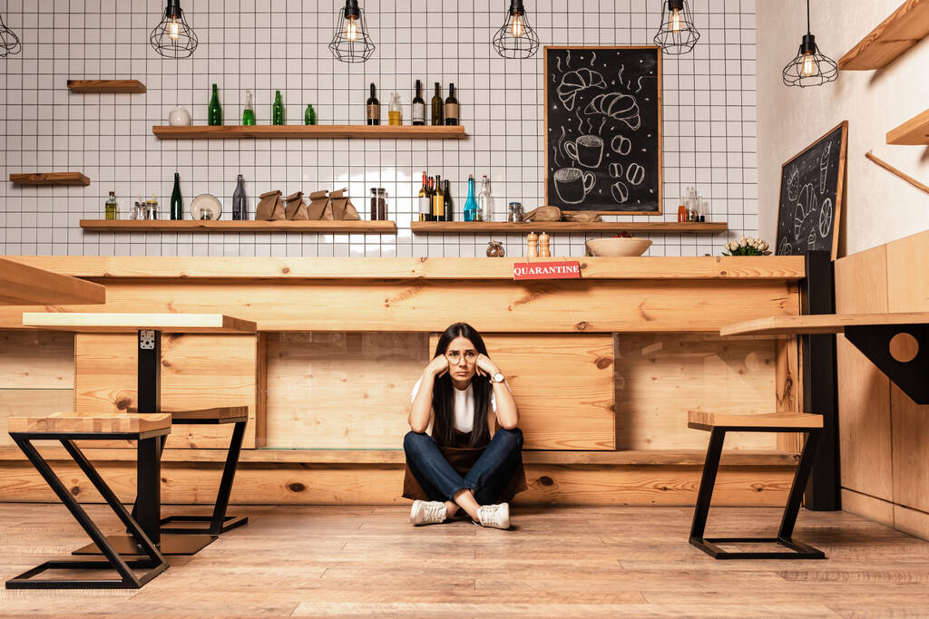Власник кафе з схрещеними ногами сидить на підлозі біля столу
 - Фото, зображення