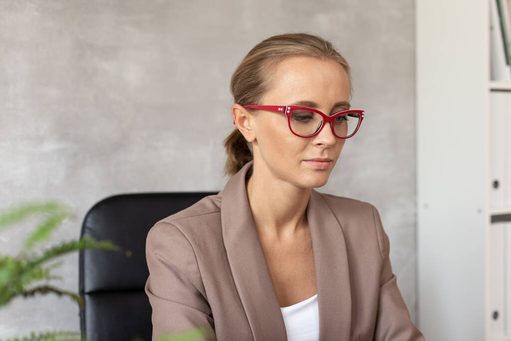 Carino donna bionda in occhiali seduta sulla sedia dell'ufficio
 - Foto, immagini