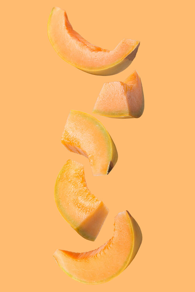 Frutos voadores isolados. Caindo melão isolado em fundo laranja com caminho de recorte como elemento de design de pacote e publicidade. vertical
. - Foto, Imagem