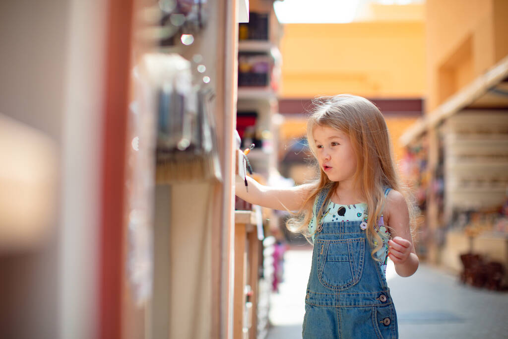 A kislány szuveníreket választ az utcai boltban lévő hotelben. - Fotó, kép