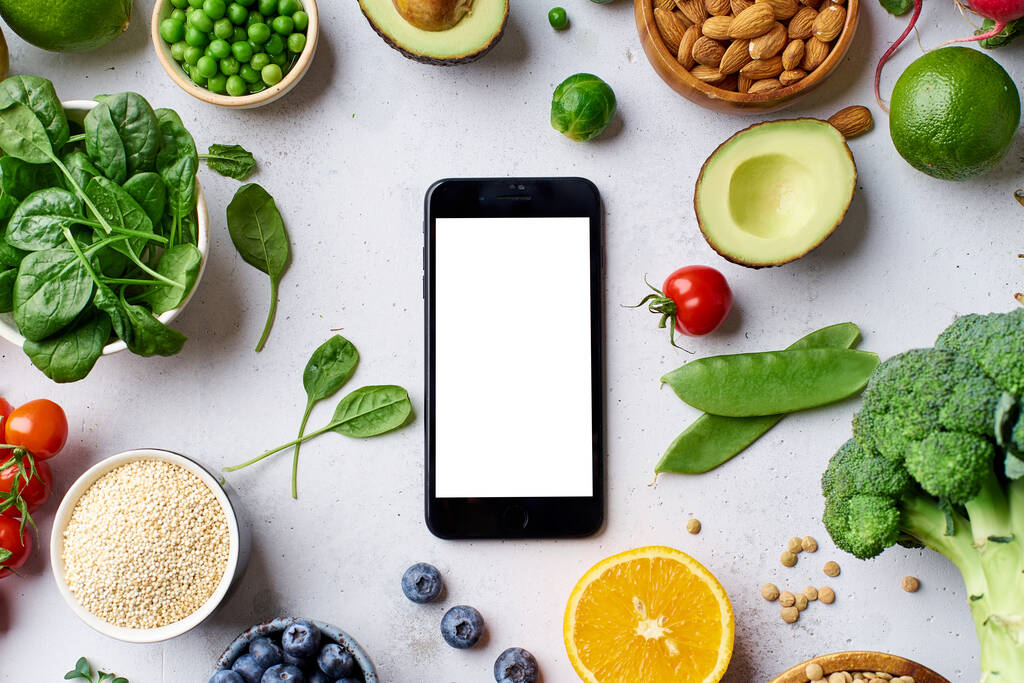 Креативна квартира з інгредієнтами вегетаріанської їжі та смартфоном з порожнім екраном. Концепція сирої веганської їжі
 - Фото, зображення