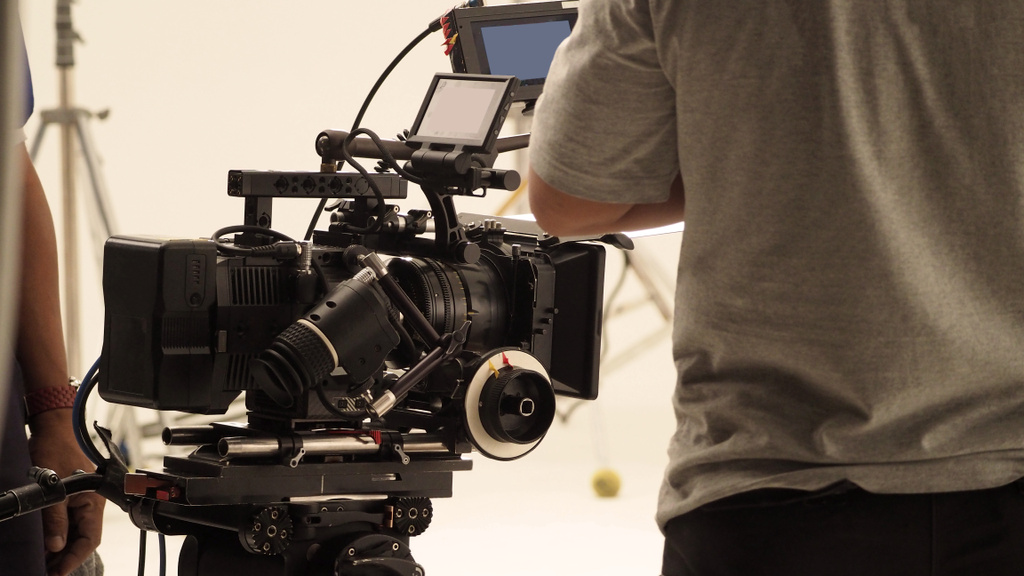 Hinter dem Shooting-Produktionsteam Team und HD-Videokamera und Ausrüstung im Studio, darunter großes Stativ, Softbox-Licht, Monitore, Objektiv für Online-Webfilm oder Film oder Live-Übertragung - Foto, Bild
