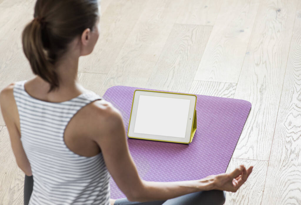 Mujer joven practicando yoga en casa. Entrenamiento en video online. Chica haciendo ejercicios y meditar. Yoga, meditación, relajación, estilo de vida saludable, concepto de entrenamiento en línea. Monitor de pantalla vacía en blanco
 - Foto, imagen