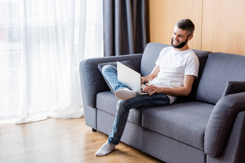 Pozitív teleworker dolgozik laptop kanapén otthon  - Fotó, kép