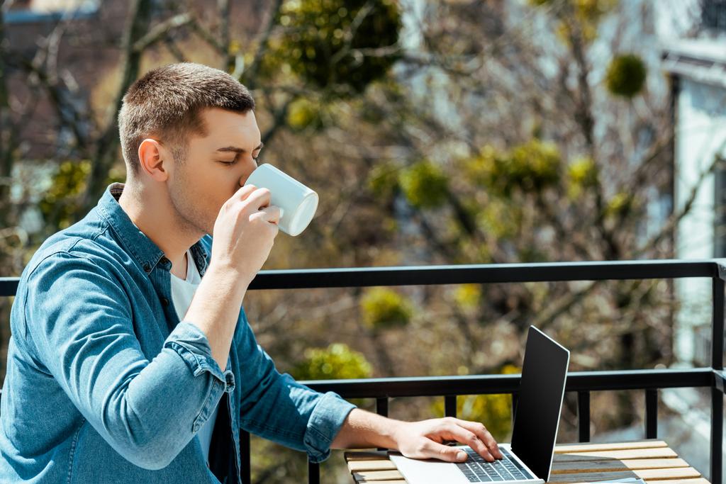 na volné noze sedící na terase s laptopem a pitím čaje - Fotografie, Obrázek