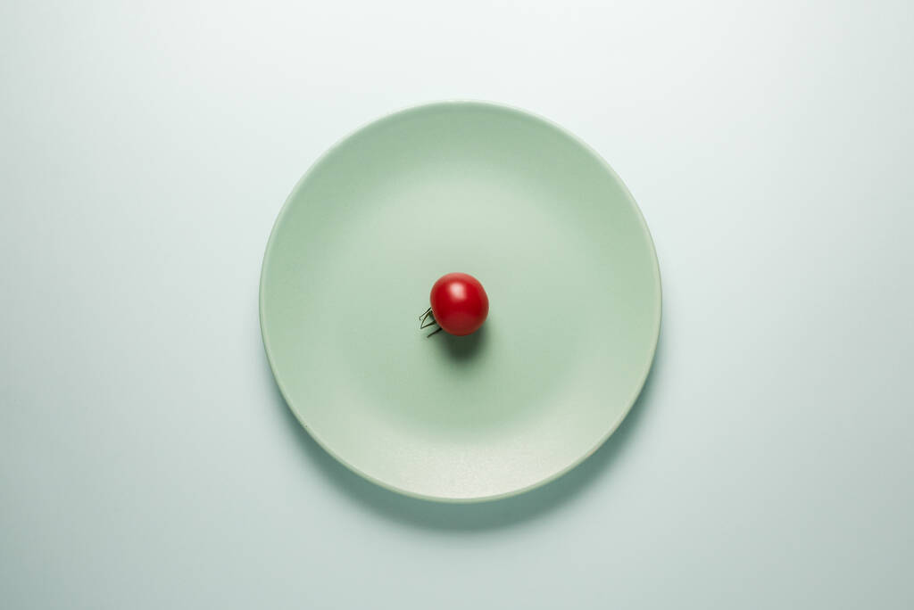 Assiette turquoise avec tomate rouge sur fond clair
. - Photo, image