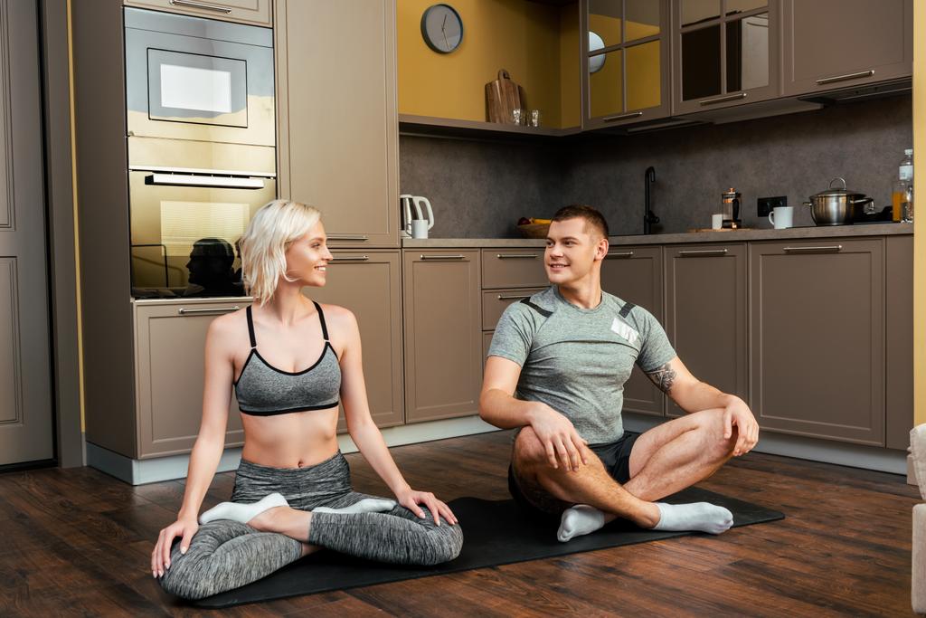 sorrindo jovem casal praticando ioga juntos em lótus posar em casa durante a quarentena
 - Foto, Imagem