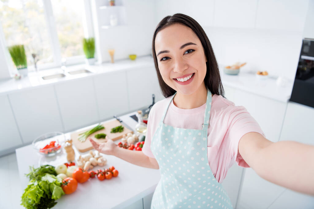 Автопортрет її вона приваблива весела весела дівчина готує викладання домашньої їжі вегетаріанської їжі для запису відео потокової майстерні в сучасному світло-білому інтер'єрі кухні
 - Фото, зображення