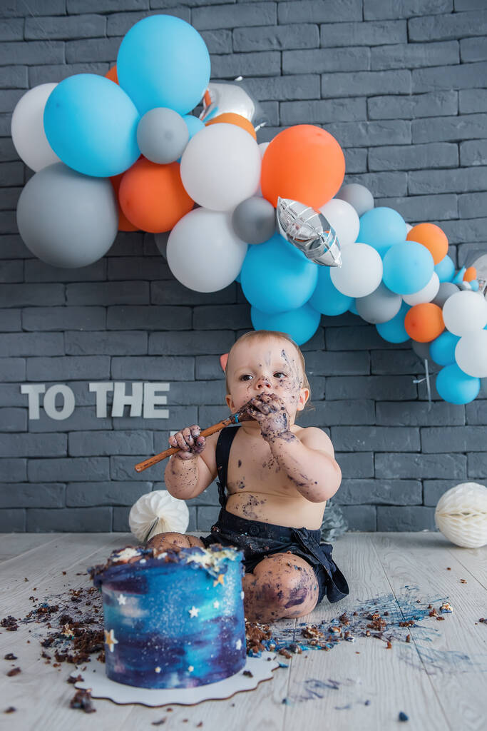 El niño celebra su primer cumpleaños en la vida. El chico come y salpica su pastel de cumpleaños. ¿Quién es? Dulce fiesta
. - Foto, Imagen