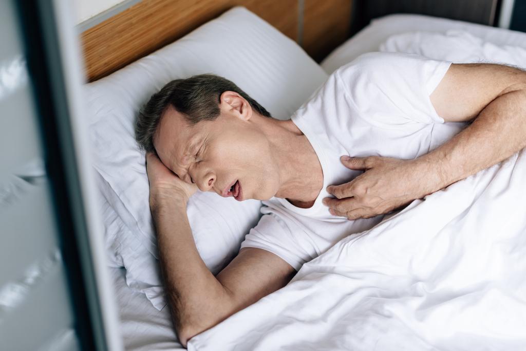 felső kilátás beteg ember köhögés, miközben feküdt az ágyon  - Fotó, kép