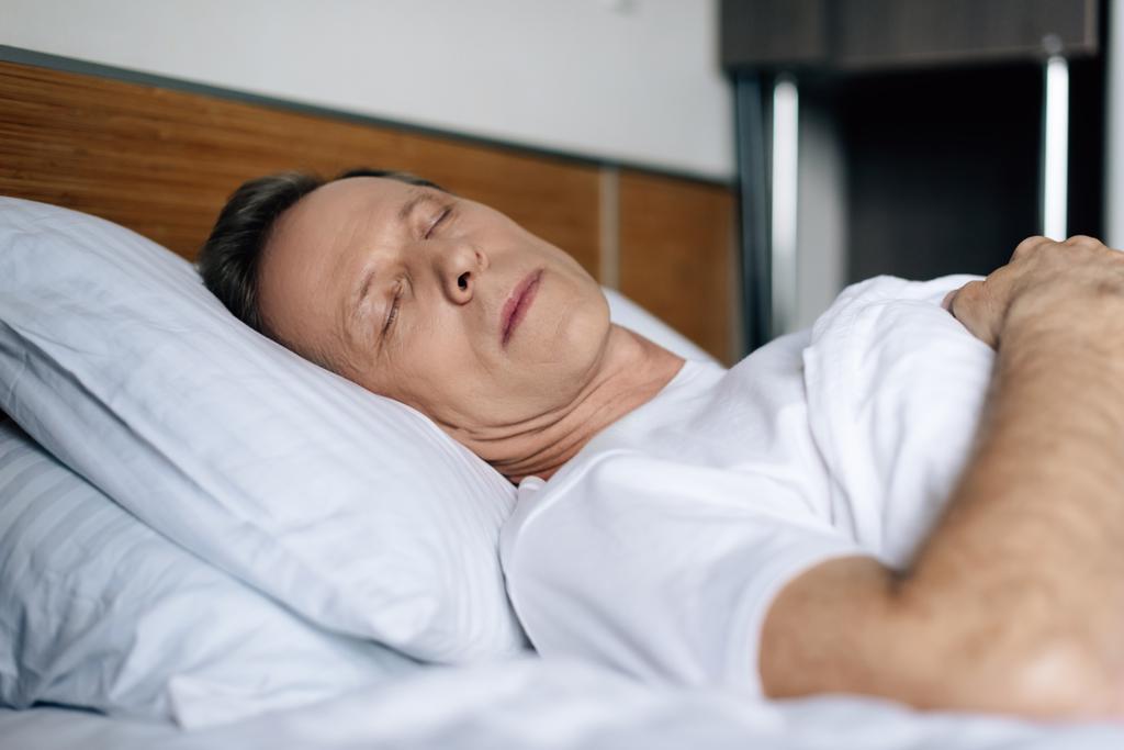 επιλεκτική εστίαση του άνδρα που κοιμάται στην κρεβατοκάμαρα  - Φωτογραφία, εικόνα