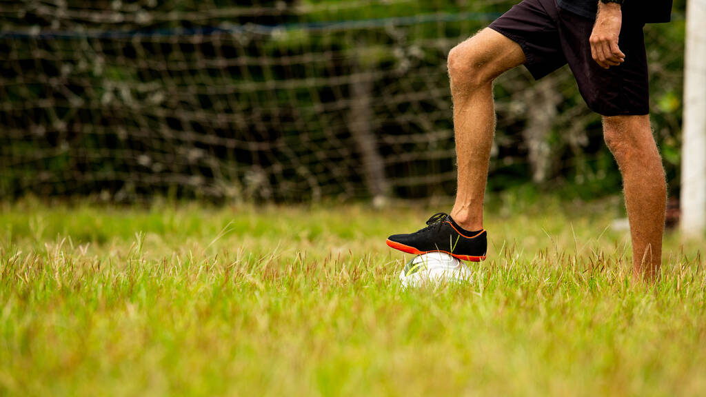 bijgesneden van volwassen sportieve man voetballen buiten - Foto, afbeelding
