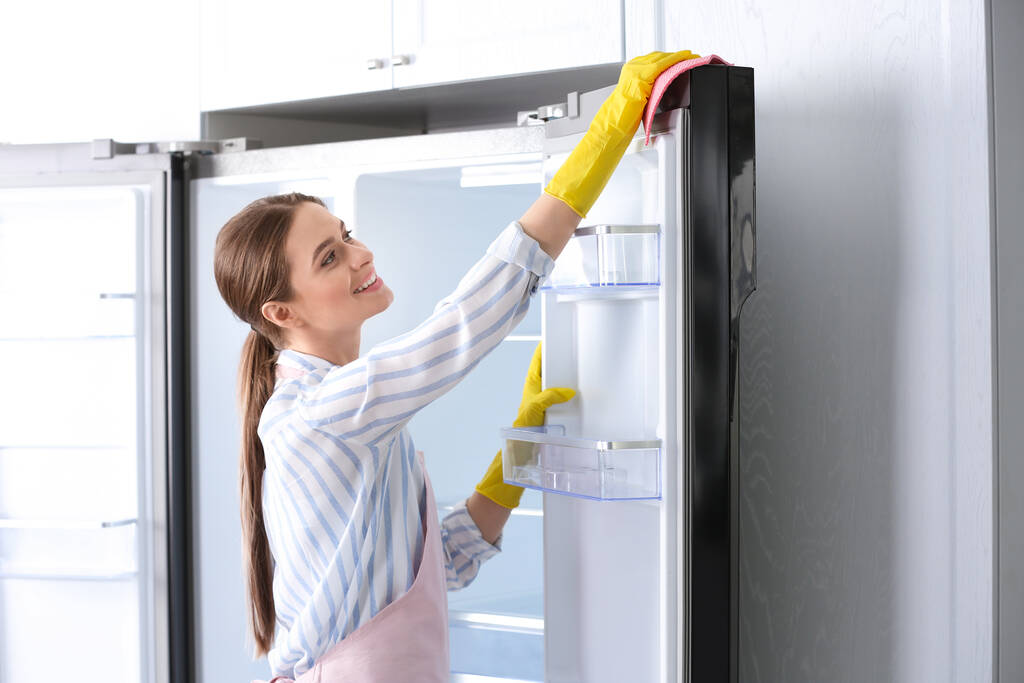 Femme en gants de caoutchouc nettoyage réfrigérateur à la maison - Photo, image
