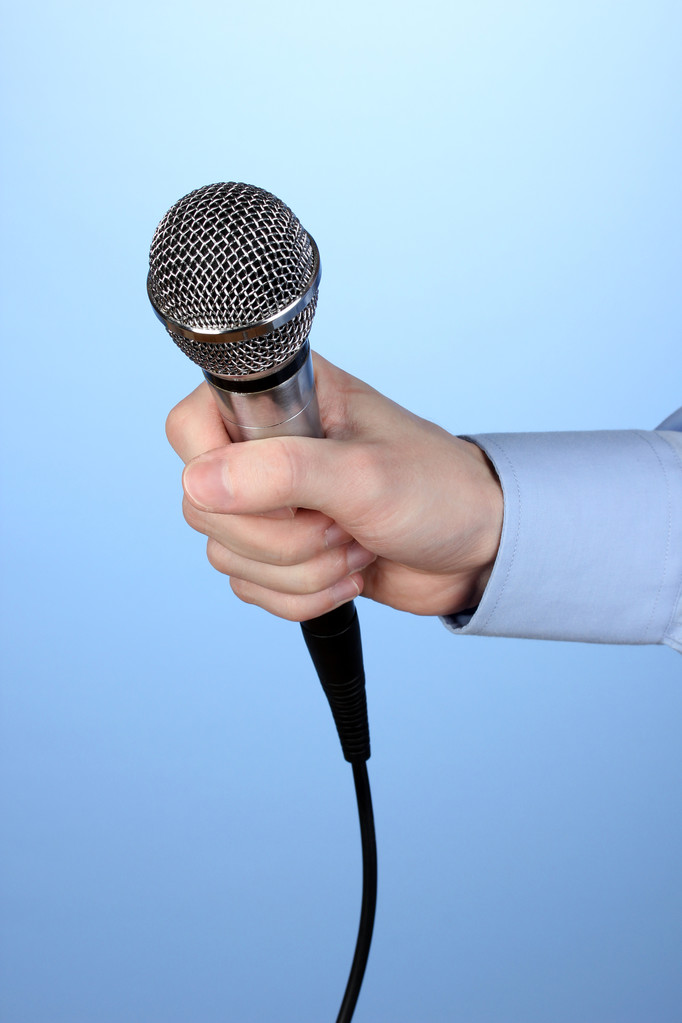 Male hand with microphone on blue background - Photo, Image