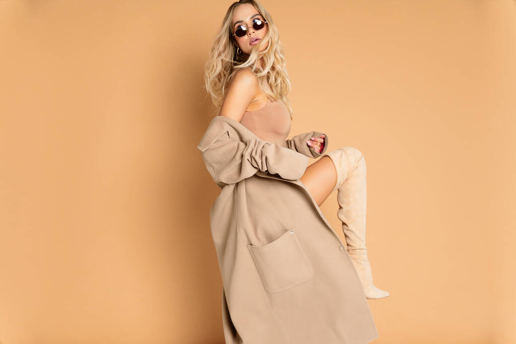 Модна красива блондинка модель позує дуже сексуально з бежевим пальто в студії повне ретушоване фото ідеальної шкіри і дуже красивої дівчини, приємної для журналу або фону
 - Фото, зображення