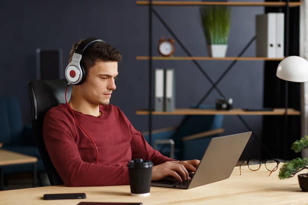 Fiatal szabadúszó dolgozik otthoni irodában laptop és listenin - Fotó, kép