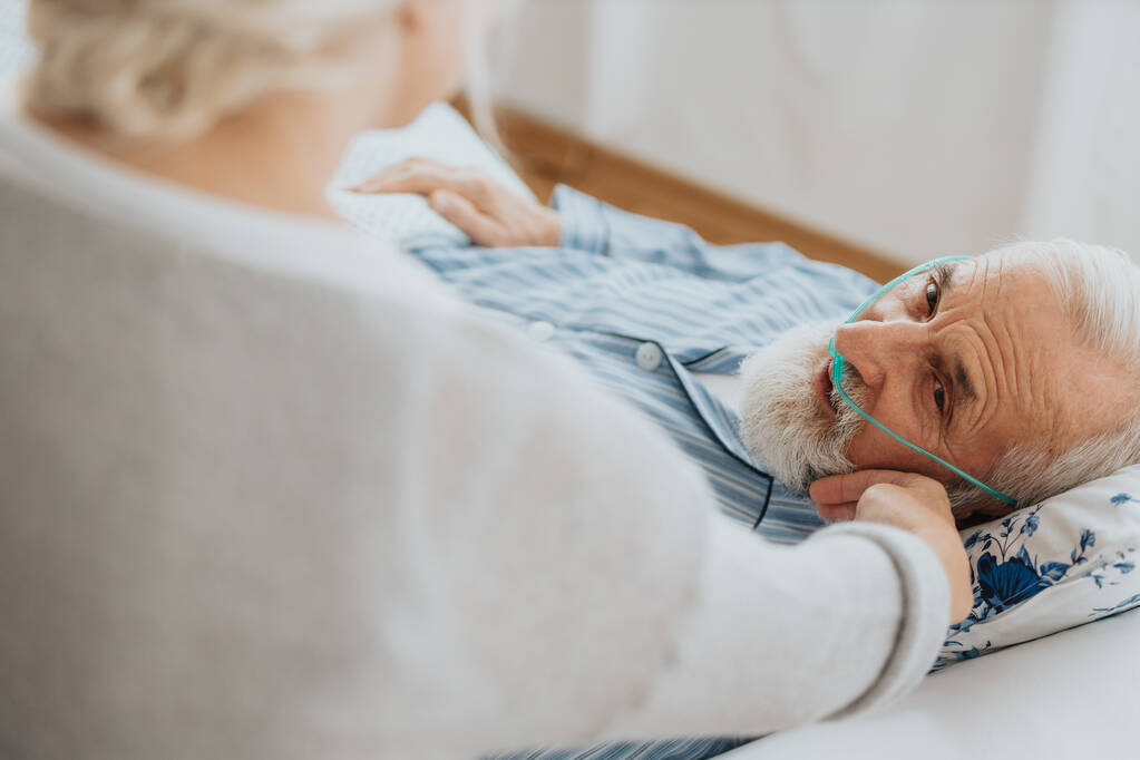 Seniorin stützt ihren sterbenden Mann im Krankenhausbett - Foto, Bild