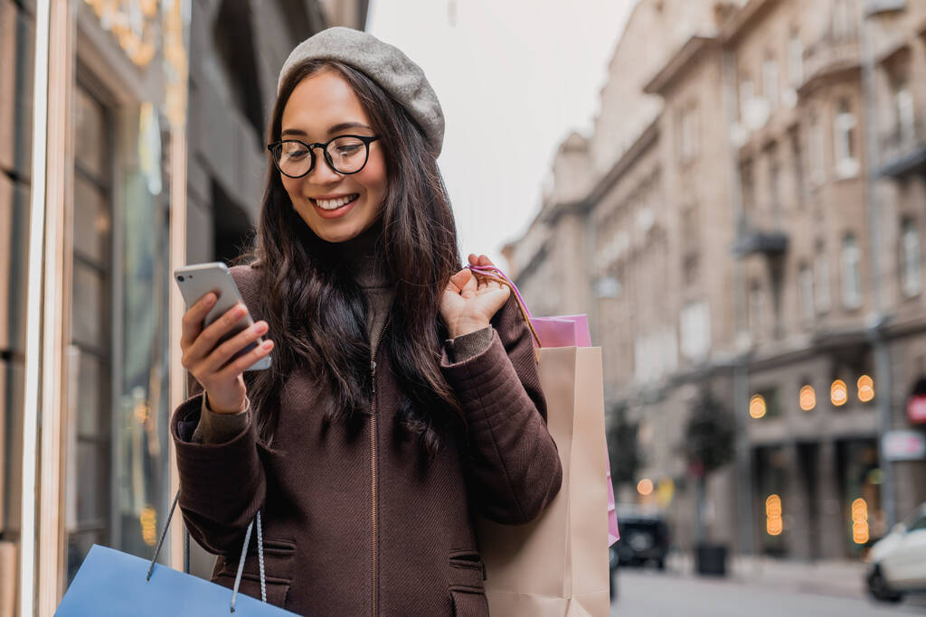 Fiatal ázsiai nő sms miközben élvezi a napi vásárlás - Fotó, kép