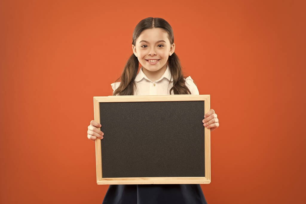 шкільні продажі. повернутися до школи. щасливий день вчителя. 1 вересня. маленька дівчинка демонструє оголошення. щаслива маленька школярка з крейдою. дошка для копіювання простору. інформація. пишіть hometak
 - Фото, зображення