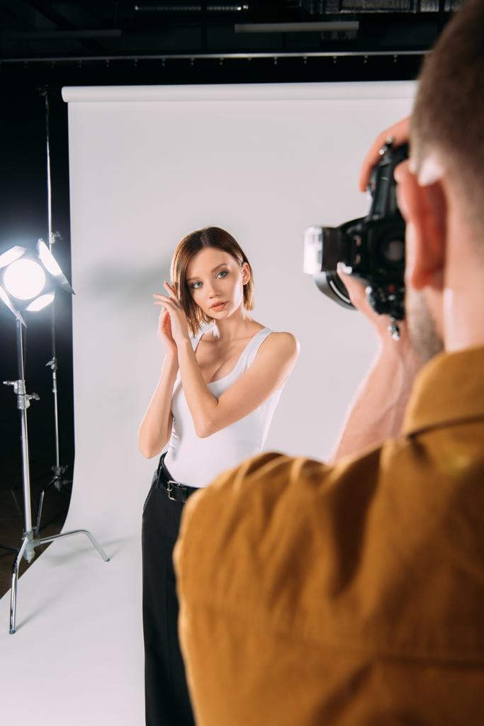 Selective focus of photographer taking photo of beautiful model in photo studio  - Photo, Image