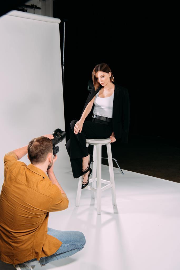 Fényképész dolgozik gyönyörű modell pózol széken fotós stúdió  - Fotó, kép