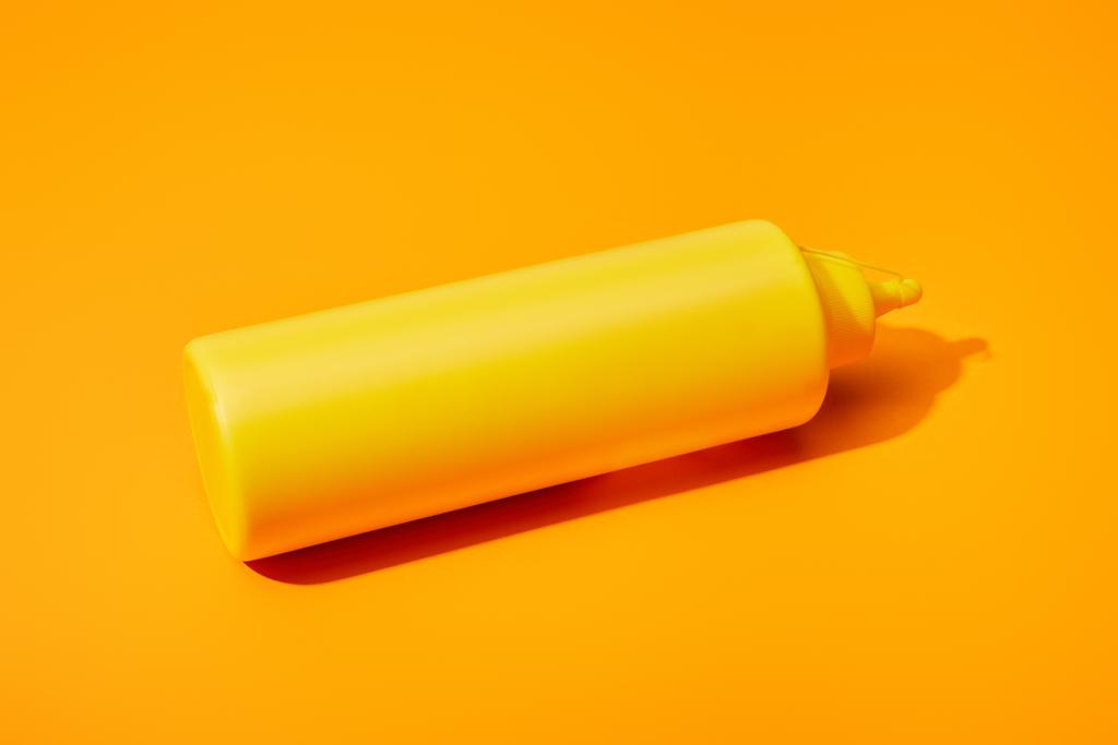 botella de mostaza sobre fondo de color naranja
 - Foto, imagen