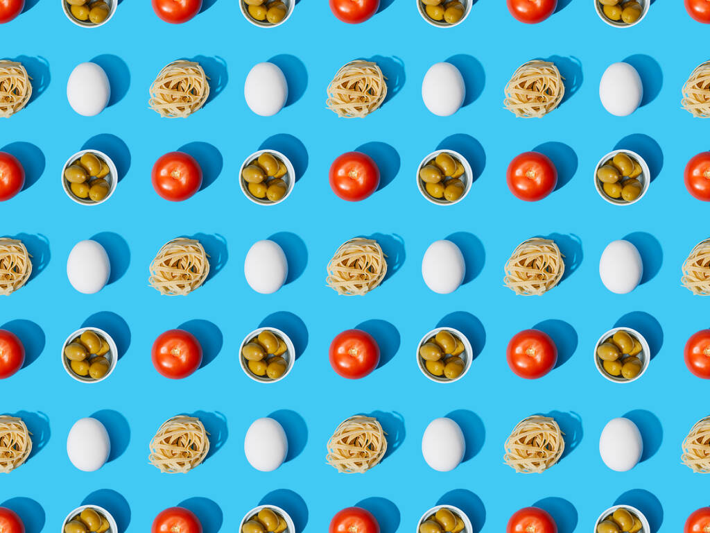 Draufsicht auf frische Pasta mit Oliven, Tomaten und Eiern auf blauem Hintergrund, nahtloses Muster - Foto, Bild