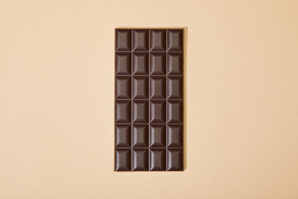 vista superior de la barra de chocolate negro dulce sobre fondo beige
 - Foto, Imagen