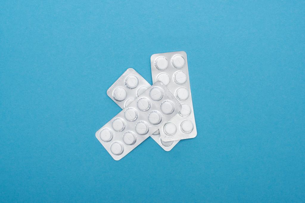 vista superior de pílulas em embalagens blister no fundo azul
 - Foto, Imagem