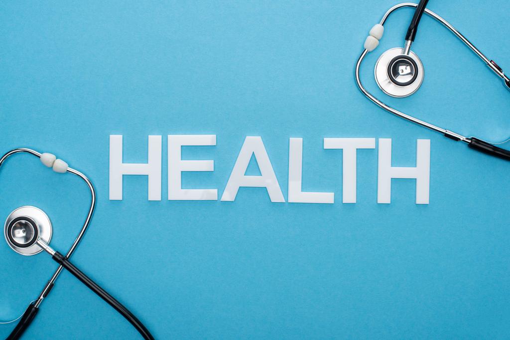 ylhäältä näkymä terveyden kirjoituksia ja stetoskoopit sinisellä pohjalla
 - Valokuva, kuva