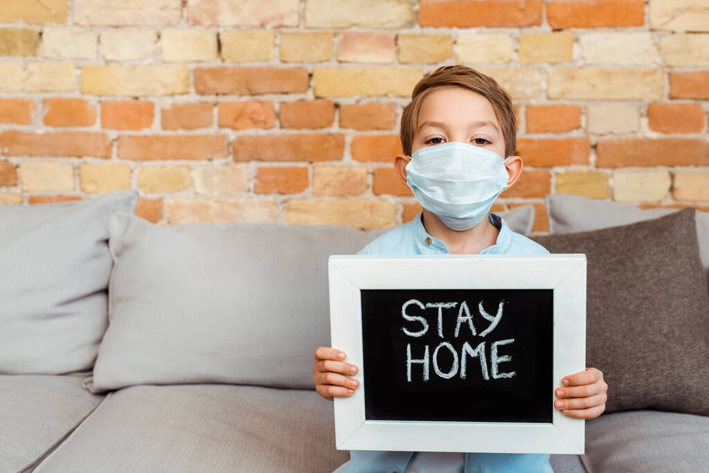 menino em máscara médica segurando quadro com ficar em casa lettering
  - Foto, Imagem