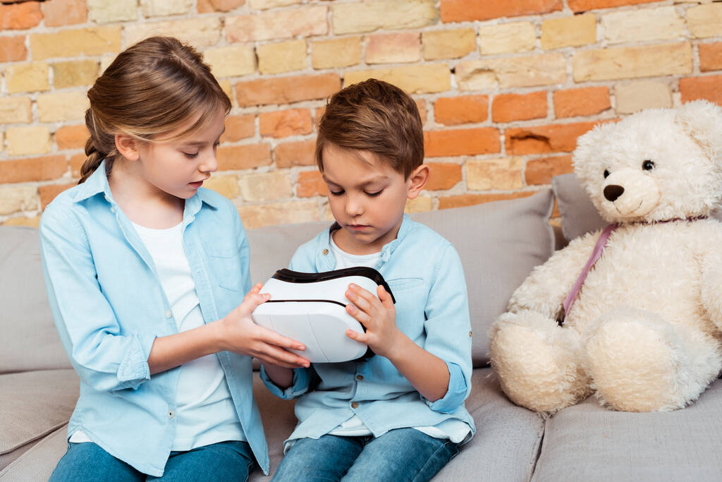 Geschwister betrachten Virtual-Reality-Headset im Wohnzimmer  - Foto, Bild