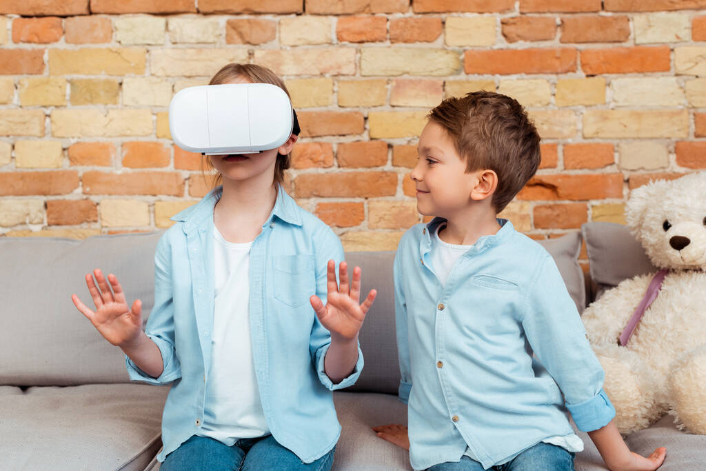 happy brother looking at sister in virtual reality headset  - Photo, Image