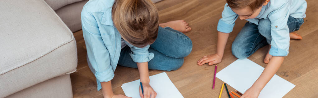 panoramic crop of sister and brother sitting on floor and drawing in living room  - Photo, Image