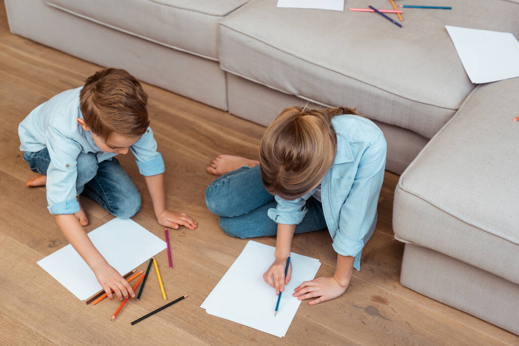 сестра и брат сидят на полу и рисуют в гостиной
  - Фото, изображение