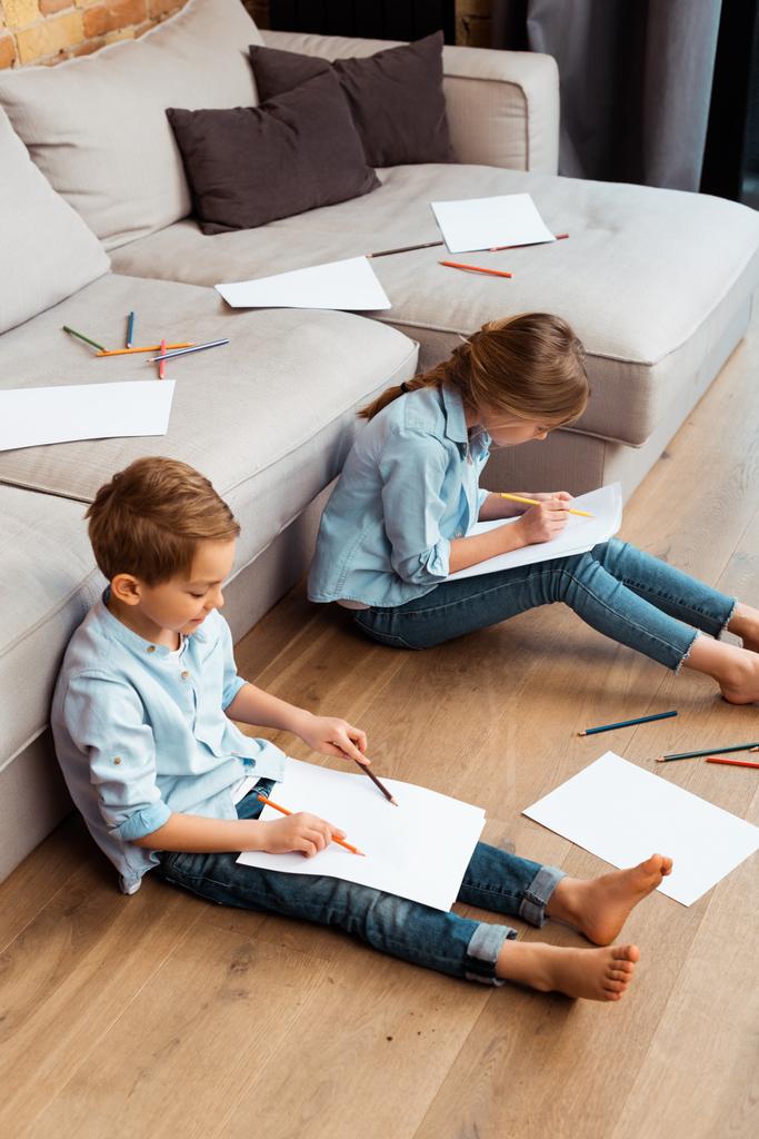 cute brother and sister sitting on floor and drawing in living room  - Photo, Image