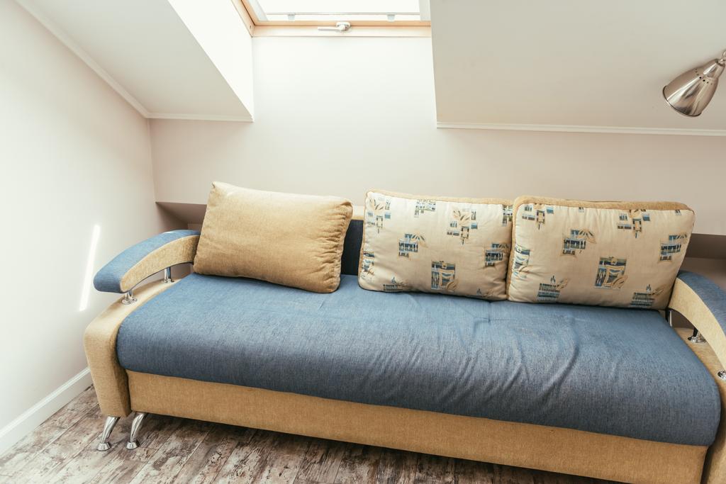 затишна мансардна кімната з вікном, і зручний диван з подушками
 - Фото, зображення