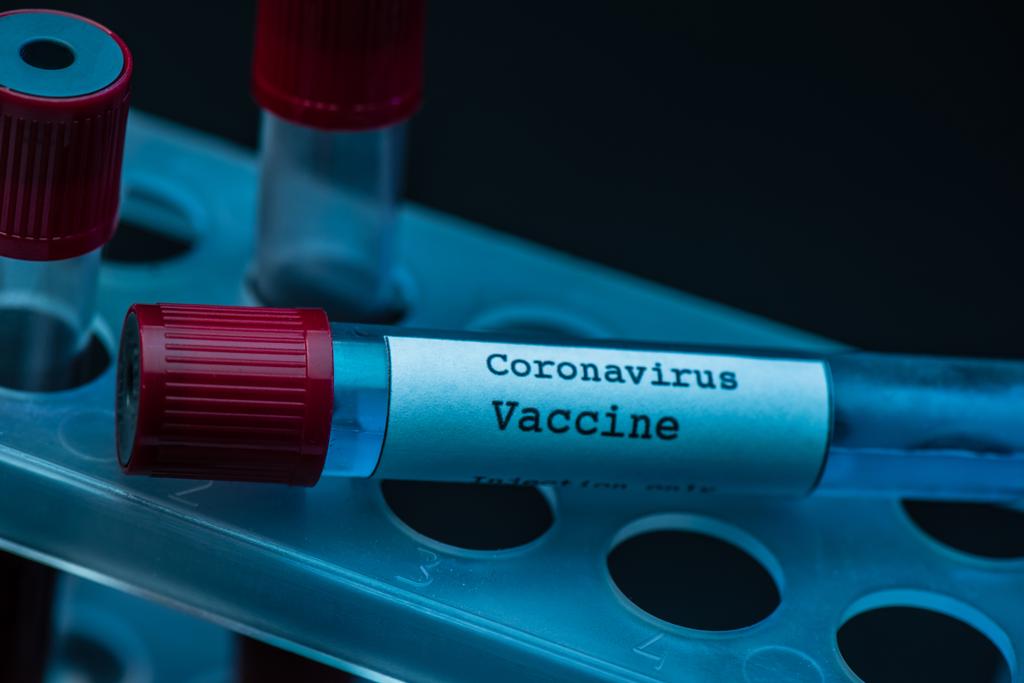 Stojan na zkumavky s koronavirovou vakcínou na tmavém pozadí - Fotografie, Obrázek