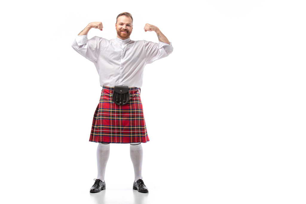 sonriente escocés pelirrojo en escocés rojo mostrando los músculos sobre fondo blanco
 - Foto, imagen