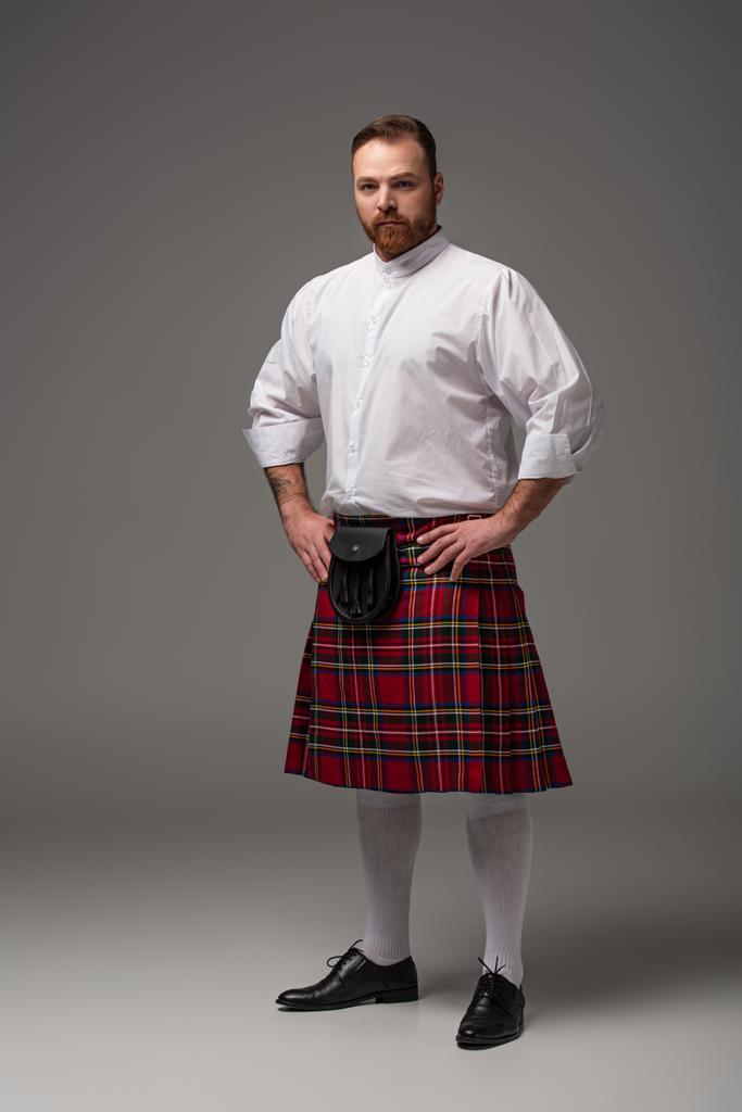 Skotlantilainen punapää mies punaisessa kiltissä harmaalla pohjalla
 - Valokuva, kuva