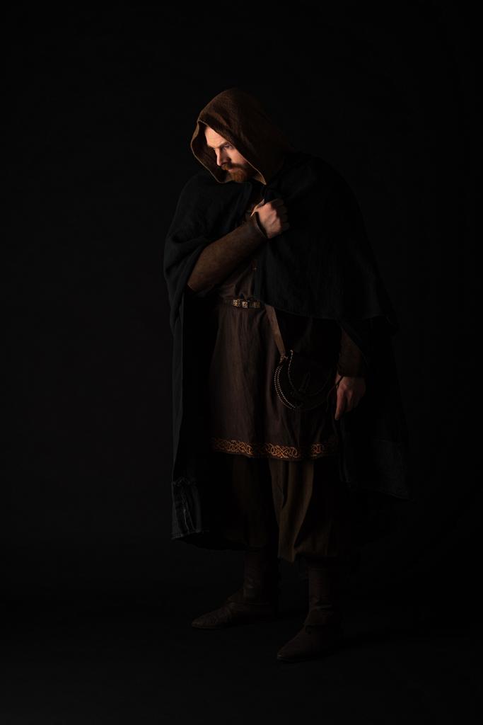 middeleeuwse Schotse roodharige man in mantel op donker geïsoleerd op zwart - Foto, afbeelding