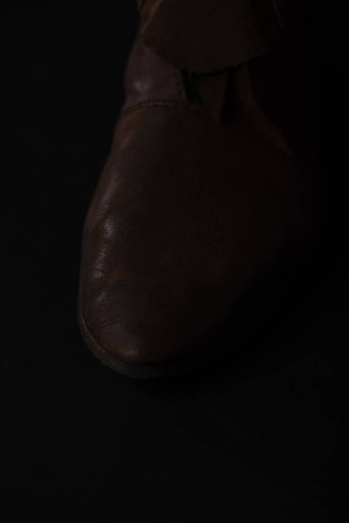 z bliska widok średniowiecznych szkockich brązowych skórzanych butów izolowanych na czarno - Zdjęcie, obraz