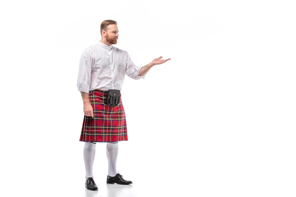 Skotlannin punapää parrakas mies punainen tartan kiltti osoittaa käsi valkoisella taustalla
 - Valokuva, kuva