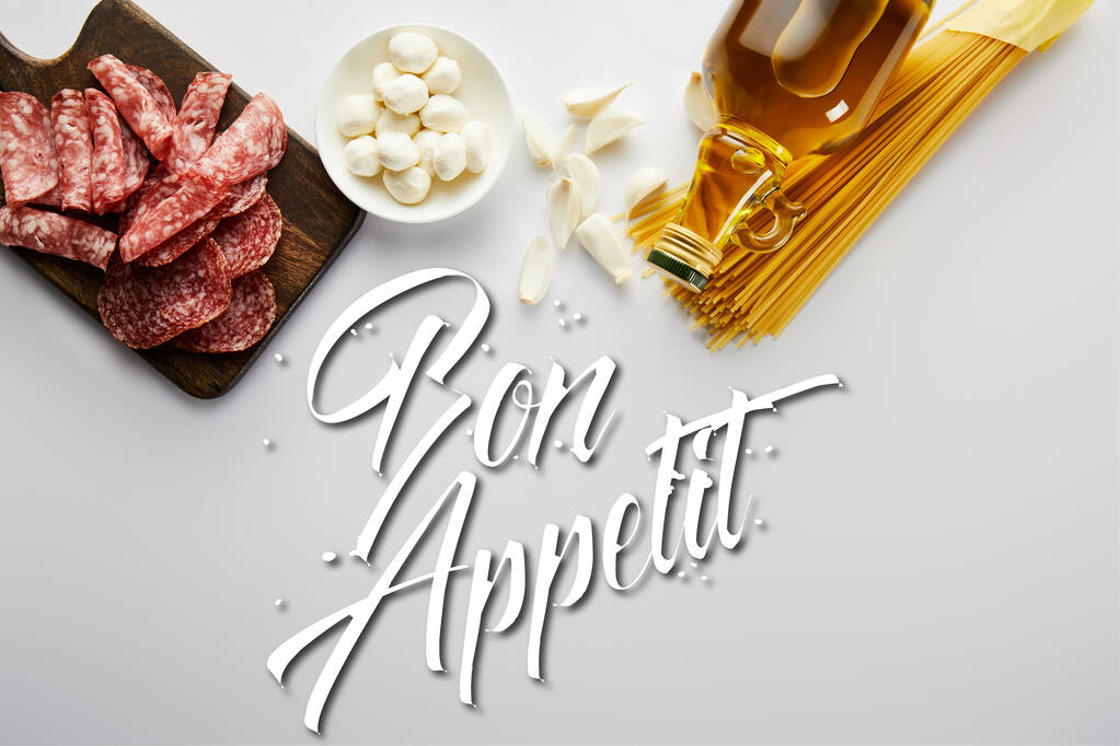 Вид сверху на бутылку оливкового масла, мясную тарелку, чеснок, пасту и миску с моцареллой на белом фоне, иллюстрация аппетита
 - Фото, изображение