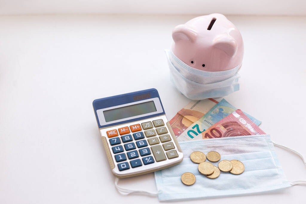 piggy bank wearing protective face mask with euro money on white background. Money saving concept in time of coronavirus pandemic. - Photo, Image