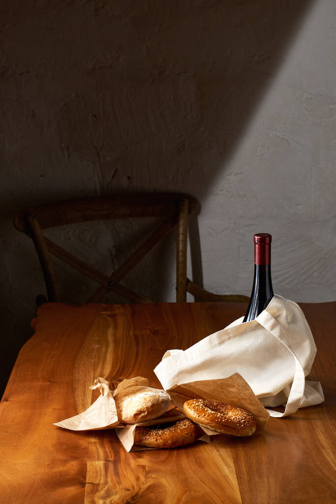 Sacchetto di tessuto bianco ecologico con vino e prodotti del pane, su un tavolo di legno con spazio copia, terra senza plastica
 - Foto, immagini